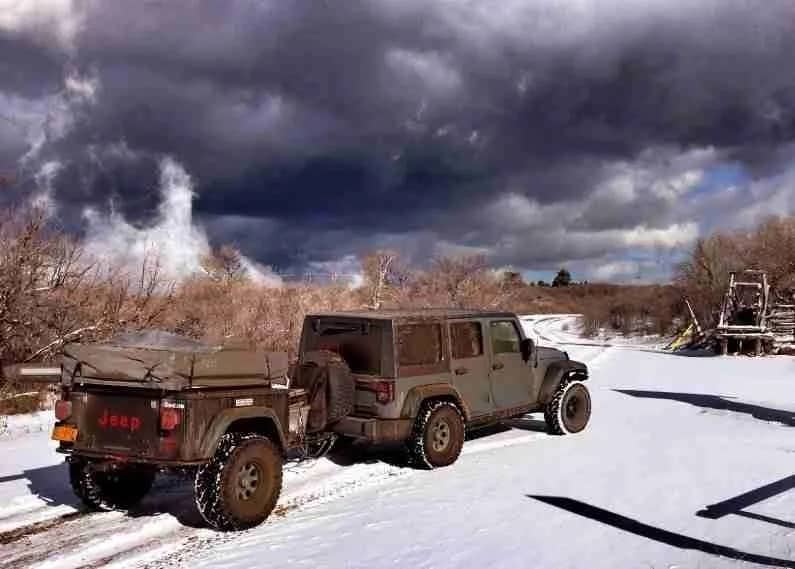 Jeep with Jeep style Dinoot Compact Camping Trailer in snowy storm
